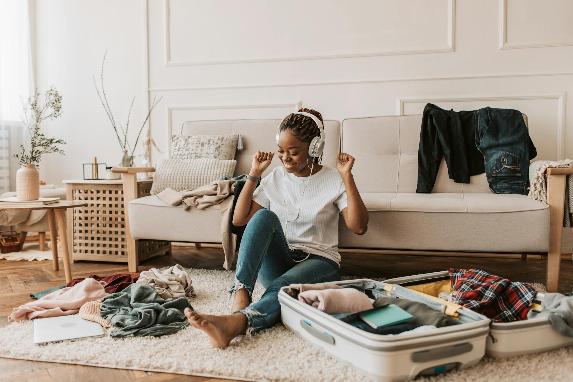A person wearing headphones at home, sorting clothes on the floor while listening, looking relaxed